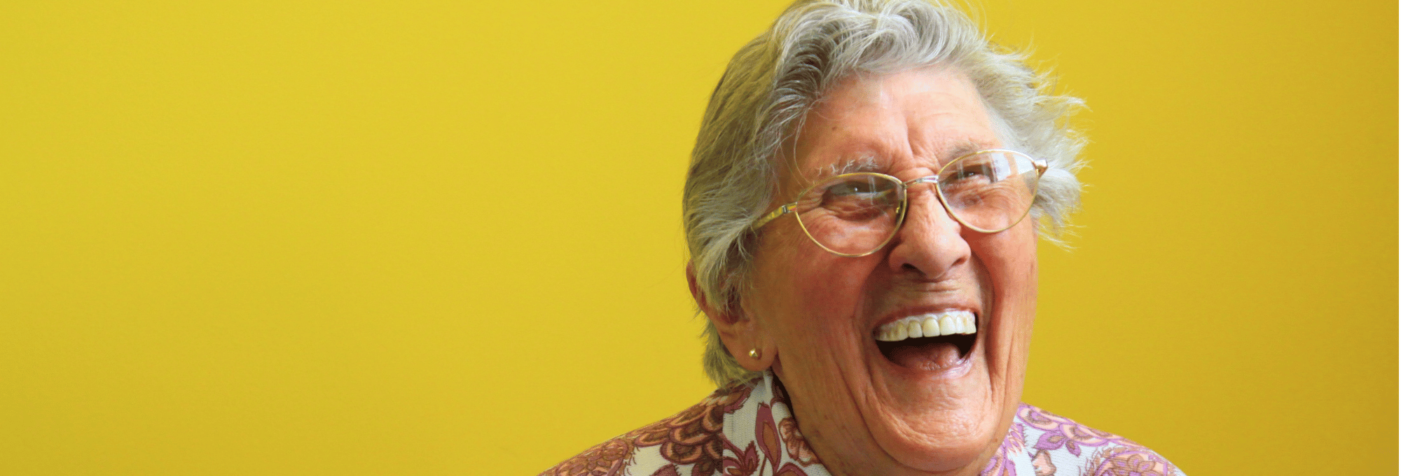 Das Bild zeigt eine sehr fröhlich lachende Seniorin.
